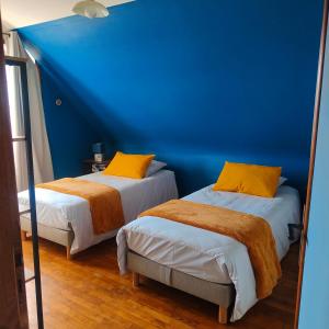 - 2 lits dans une chambre avec un mur bleu dans l'établissement Chez Dom et Pascal, à Plestin-les-Grèves