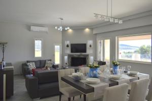 Un comedor y una sala de estar con mesa y sillas. en Gaia Luxury Villa, en Ermioni