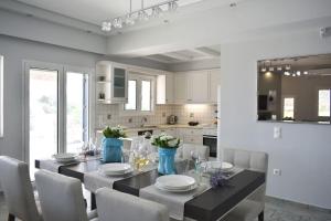 cocina con mesa de comedor con sillas blancas en Gaia Luxury Villa, en Ermioni