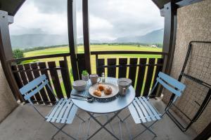 ein Tisch mit einem Teller Essen auf einem Balkon in der Unterkunft Le Doux Art de Vivre - Studio 2 personnes avec vue in Doussard