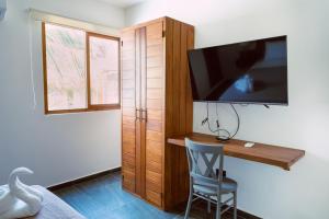 a bedroom with a desk with a tv and a chair at Casa La Martina Holbox in Holbox Island