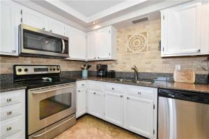 une cuisine avec des armoires blanches et des appareils en acier inoxydable dans l'établissement Enclave 602a by Gulf Tide Vacation Rentals, à Destin