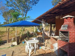 a patio with a table and a blue umbrella at Aconchego Santa Luzia in Pirenópolis +32 photos