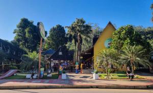 a park with a large yellow building with palm trees at Chalé 05 com hidro e cozinha no coração de Penedo in Itatiaia