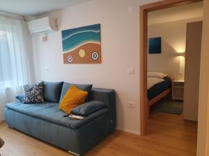 a living room with a blue couch and a bed at Apartmaji Pregelj in Koper
