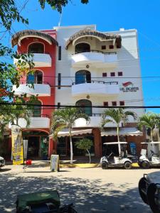 a tall building with palm trees in front of it at Hotel y Suites Los Encantos in Sayulita
