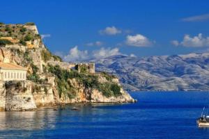 a boat sitting on the water next to a mountain at Adelia's Luxury Studio in Corfu in Corfu +17 photos