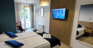 a hotel room with two beds and a tv on the wall at Cicha Przystań - Pokoje Przy Latarni in Kołobrzeg