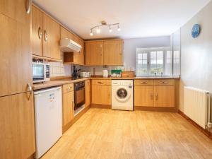 a kitchen with wooden cabinets and a washer and dryer at Llys-y-Wennol in Betws-y-coed +14 photos