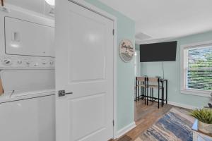 a white kitchen with a stove and a tv at 6-Min Walk to Asbury Park & OG Main St - Updated & Cozy Apartment in Historic Ocean Grove - Fire Pit & Patio - Fast Wi-Fi in Ocean Grove