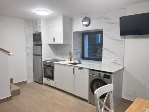 a white kitchen with a sink and a dishwasher at La casina de Tomás in Colunga