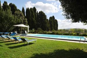 a swimming pool with lawn chairs and an umbrella at Casa Vacanze Vigna di Valle in Bracciano