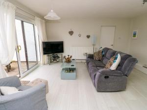 Una sala de estar con un sofá y un televisor. en Sunset Sands, en Conwy