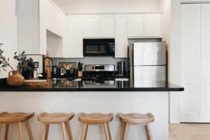 a kitchen with white cabinets and a counter with stools at The Monarch - Chic 1BR Pools and Views in Old Town La Quinta in La Quinta