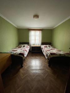 two beds in a room with green walls and a window at Guest House Buba in Ushguli