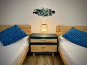 two beds with blue pillows and a night stand with a lamp at Gure Toki Algorta cerca de la playa y de la ciudad in Getxo