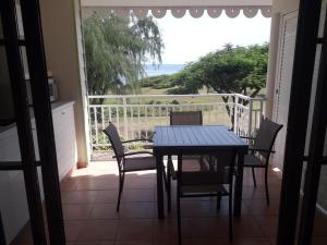 a table and chairs on a balcony with a view of the ocean at Le Colibri du Paradis in Sainte-Anne