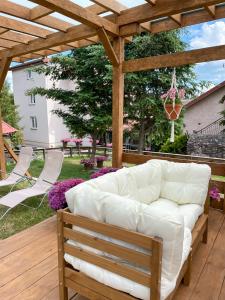 a white couch sitting under a wooden pergola at Agroturystyka z Alpakami Mazury in Mrągowo