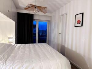 a bedroom with a large white bed with a window at Terrasse des Dunes in Knokke-Heist