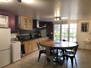 a kitchen with a table and chairs and a refrigerator at Gîte de la Rhumerie in Frampas