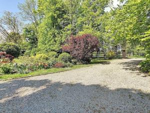 a gravel driveway with trees and bushes in a yard at Gîte de la Rhumerie in Frampas