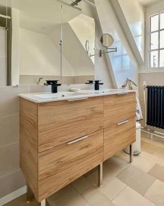a bathroom with a sink and a large mirror at Le Lampadaire du Martreuil in Pierrefonds