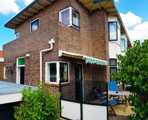 ein Backsteinhaus mit einer Terrasse und einem Tisch in der Unterkunft Have a nice stay! - Strand Vakantiehuis Noordwijk in Noordwijk aan Zee