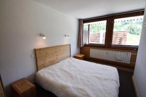 sypialnia z łóżkiem i dużym oknem w obiekcie Résidence Le Mont Blanc - 3 Pièces pour 6 Personnes 024 w Aime La Plagne