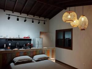 a bedroom with two pillows on a bed and a kitchen at Studio Ametista na praia do Silveira em Garopaba in Garopaba