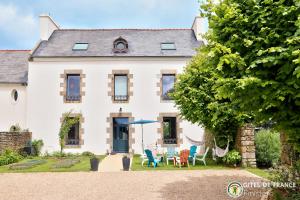 a white house with chairs and tables in the yard at Magnifique demeure à 15 min des plages 12 adultes in Saint-Renan
