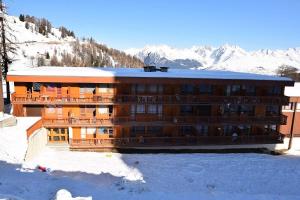 a large building in the snow with mountains in the background at Résidence Les Arolles - 2 Pièces 4 pers - LES AROLLES - PLAGNE CENTRE - WIFI MAE-7934 in Aime La Plagne