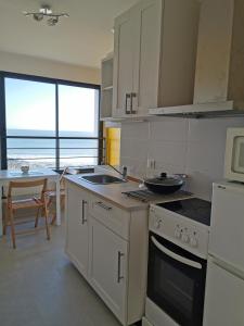 una cocina con fregadero y estufa horno superior en T3-Vue sur ocean - Pieds dans l'eau-Terasse-jardin-Parking gratuit, en Batz-sur-Mer 28 fotos más