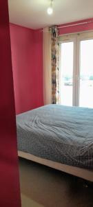 a bedroom with a bed and a red wall at Caen la mer in Caen +1 photo