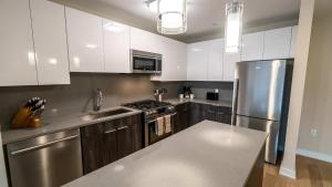 Una cocina con gabinetes blancos y un refrigerador de acero inoxidable. en Apt Downtown with Gym and Pool, en Stamford