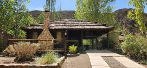 a small building with a roof in a garden at Cabin in Protrerillos near Mendoza River in Potrerillos