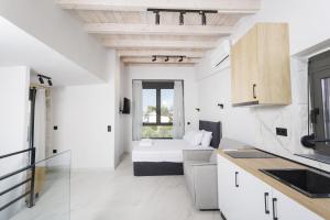a white room with a bed and a kitchen at Rigas Boutique Rooms in Pefkochori