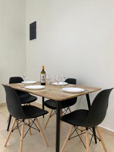 een houten tafel met stoelen en een fles wijn bij SK Apartment in Neoi Epivatai