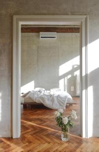 a bedroom with a bed with white sheets and a vase of flowers at Extraordinary quiet apartment in the very centre in Bratislava
