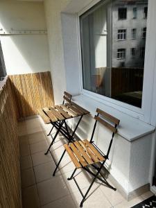 two benches sitting next to a window on a balcony at Apartament Gdynia Centrum in Gdynia