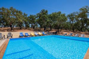 a swimming pool with chairs and trees in the background at Valle D`Água - Casas de campo in Vale de Água