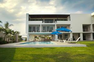 a large white house with a swimming pool and two umbrellas at Hotel Aqua Spa & Resort in Martínez de La Torre