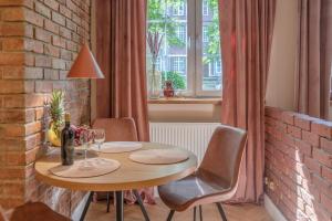 a dining room table with chairs and a brick wall at Amber Apartament in Gdańsk