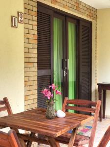 einen Holztisch mit einer Vase aus Blumen auf einer Terrasse in der Unterkunft Apartamento Studio - Solar Pipa in Pipa