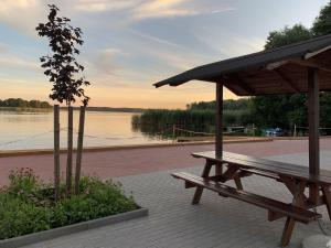 a wooden picnic table sitting next to a lake at Apartamenty Trawers in Wielen Zaobrzanski