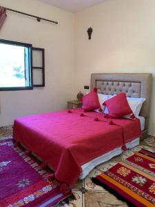 a bedroom with a large bed with red sheets and a window at Auberge Le Mouflon in Ouirgane