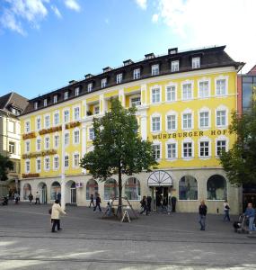 a yellow building with people walking in front of it at Hotel Würzburger Hof **** in Würzburg