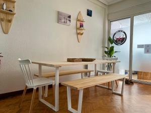 mesa y bancos en una habitación con ventana en Escuela de Surf WAVES SOUND - Alojamiento Compartido, en Santoña