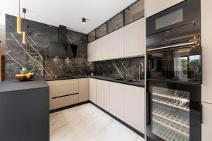 a kitchen with white cabinets and black appliances at 88 TREES Luxury Apartment in Malinska