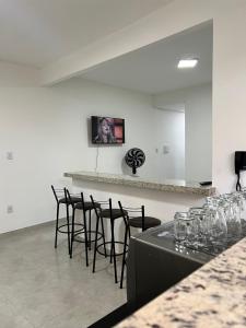 une pièce avec un bar avec des chaises et un comptoir dans l'établissement Executivo Veneza 303, à Ipatinga