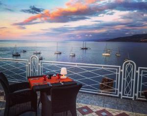 a balcony with a table and chairs and a view of the water at Hotel Kalura in Cefalù
